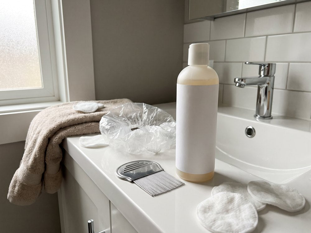 Treatment shampoo, a metal nit comb and a shower cap on a bathroom counter